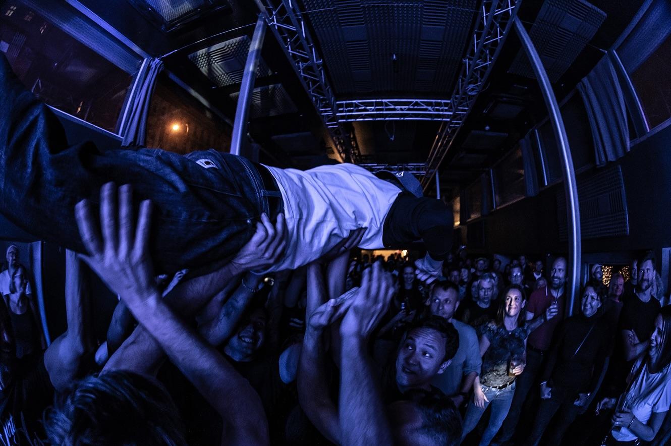 Návštěvník surfuje po rukách davu během karaoke večera v Cargo Gallery